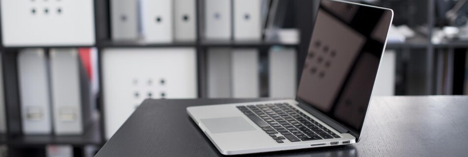 Laptop auf Schreibtisch in modernem Büro als Symbol für digitale Baugutachter Online-Beratung.
